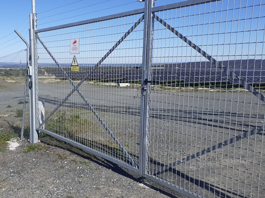 Duża podwójna metalowa brama w parku solarnym z elektronicznym systemem zamykania.